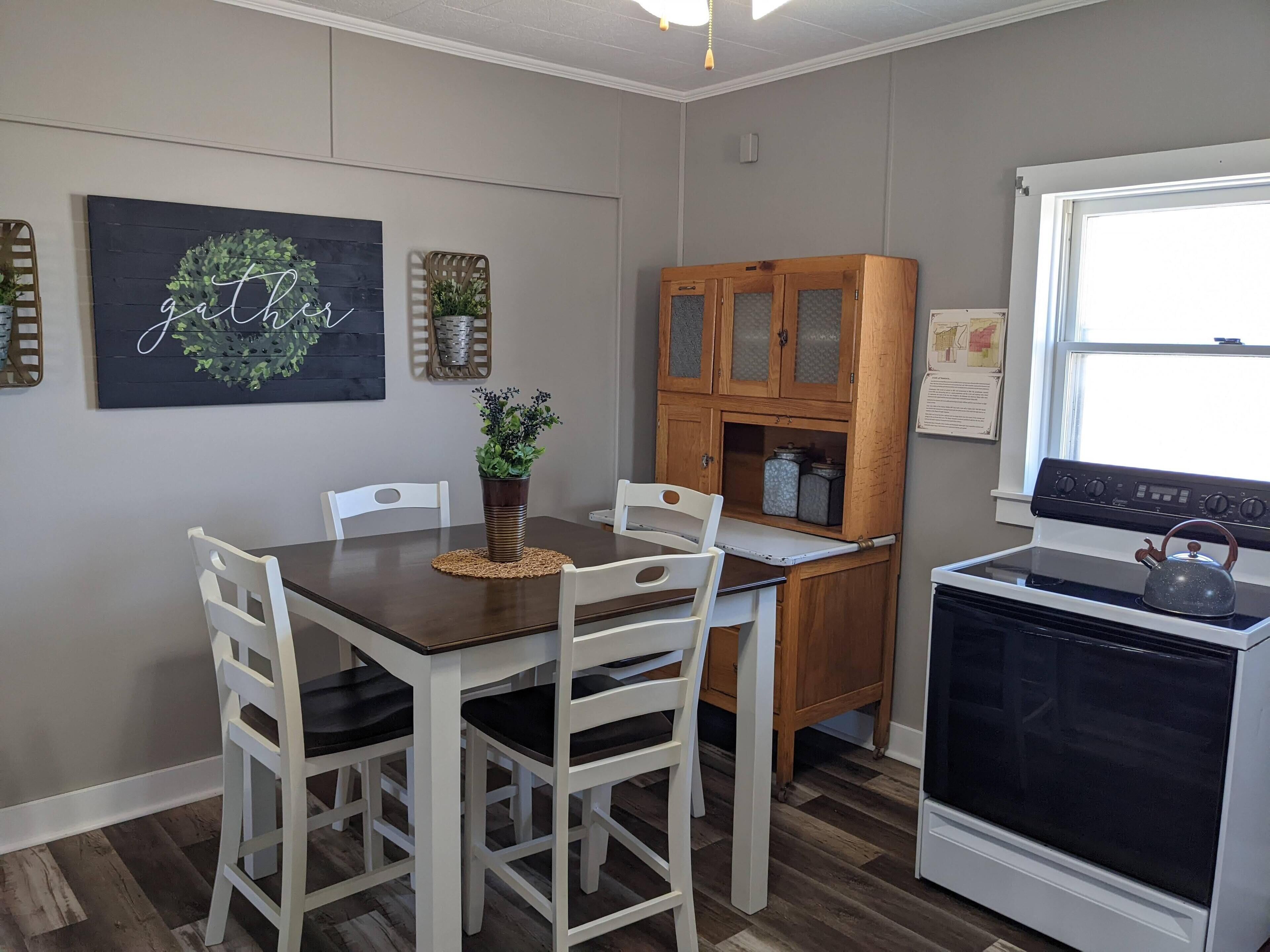 A kitchen with a dining table, chairs, a stove, and cabinets.