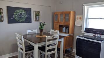 A kitchen with a dining table, chairs, a stove, and cabinets.