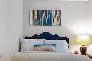 A neatly made bed with patterned pillows, a decorative headboard, and a bedside lamp.