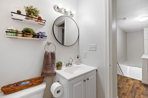 A bathroom with a white sink, mirror, and shelves with toiletries.