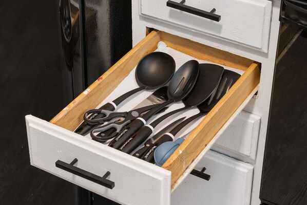 Un cajón con utensilios de cocina, incluyendo una cuchara grande, una espátula y unas tijeras.