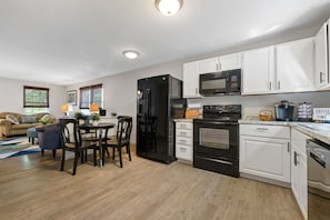 A modern kitchen with white cabinets, a black refrigerator, a microwave, and a coffee maker.