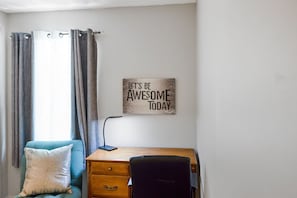 A room with a desk, chair, and a motivational sign on the wall.