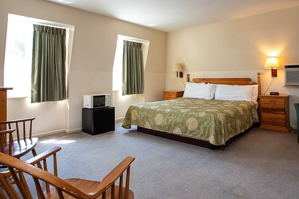 A bedroom with a bed, bedside tables, a lamp, a chair, and a desk.