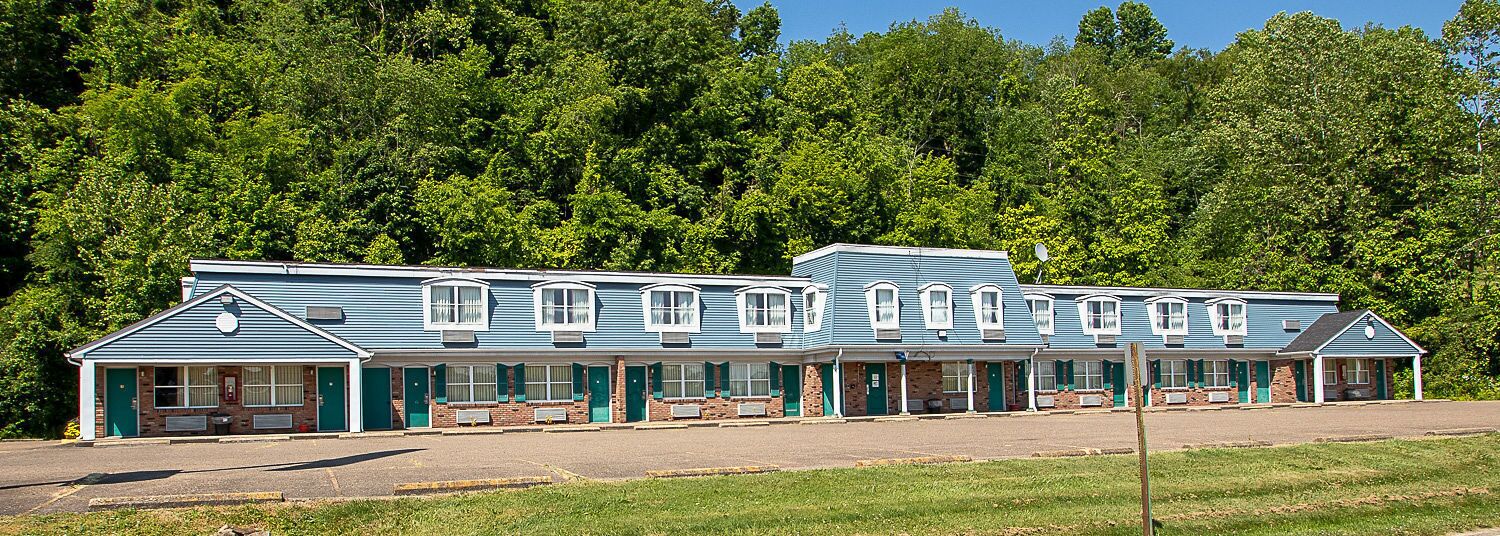 A motel with a row of rooms, each with a front porch and a brick facade.