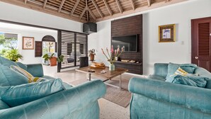 A spacious living room with a high wooden ceiling, a large TV, and teal sofas. - 🏝️ Forever Summer | Gorgeous 4BDR Villa w/ Pool - Panoramic Views (Runaway Bay)