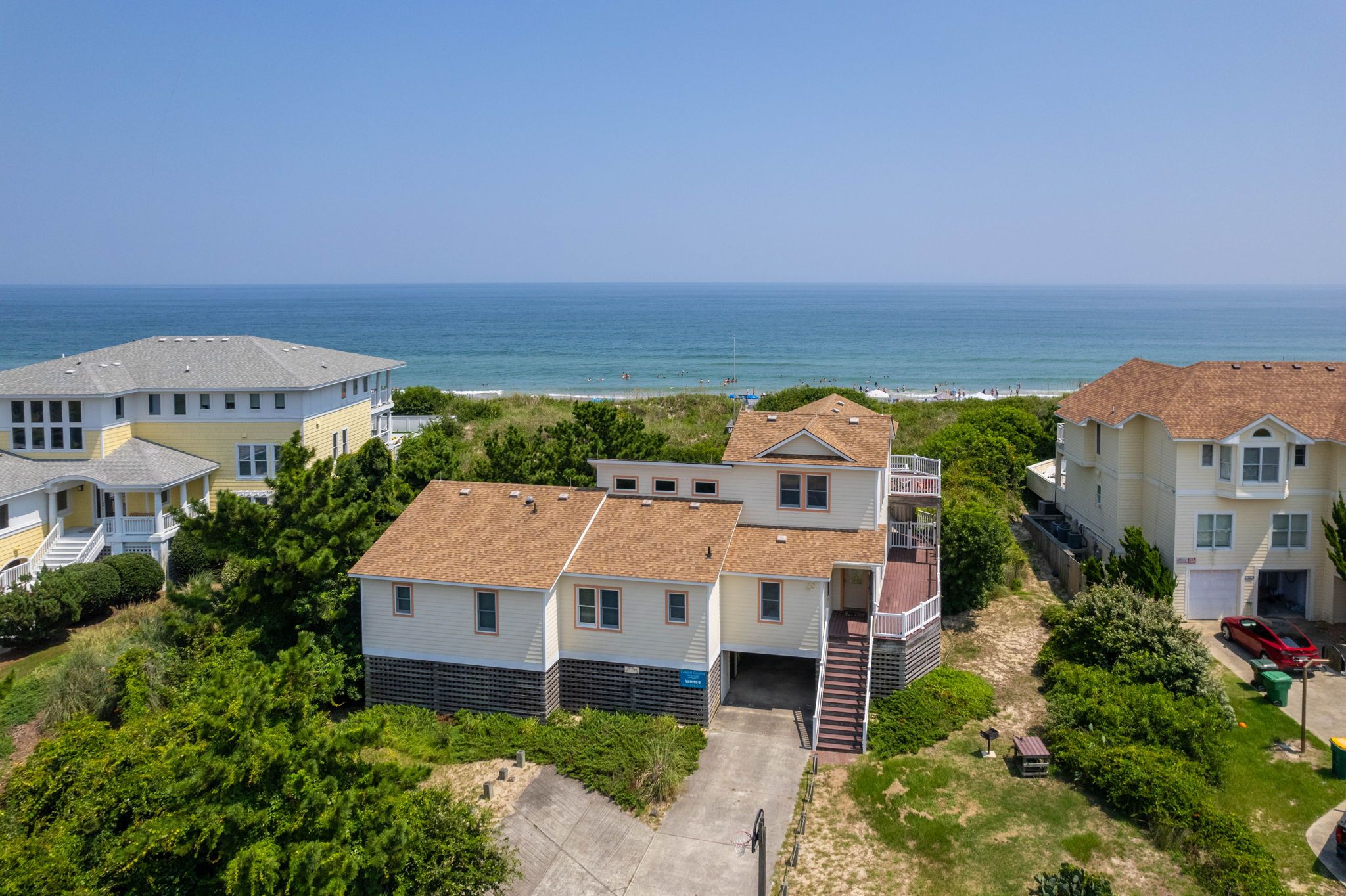 Un quartier résidentiel situé sur la côte, avec des maisons, une vue dégagée sur l’océan et une allée pavée menant à un garage.