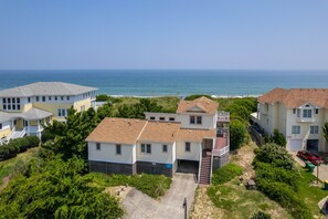 A coastal residential area with houses, a clear view of the ocean, and a paved driveway leading to a garage.