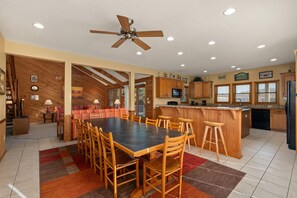 A spacious kitchen with wooden cabinets, a dining area with a large table and chairs, and a ceiling fan.