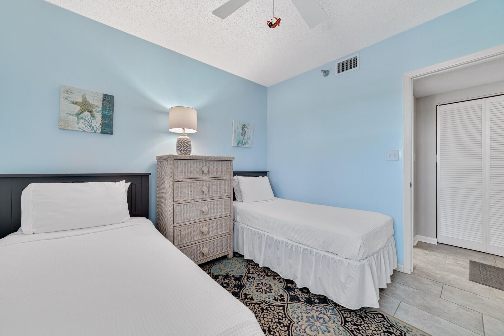A bedroom with two beds, a dresser, and a ceiling fan.