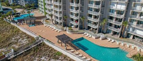 Un hotel de gran altura con varios balcones, piscina y zona de playa.