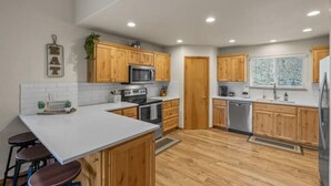 Una cucina moderna con mobili in legno, un piano di lavoro bianco ed elettrodomestici in acciaio inossidabile.