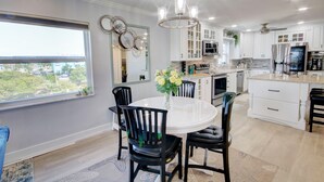 A modern kitchen with white cabinets, a round dining table, and black chairs.