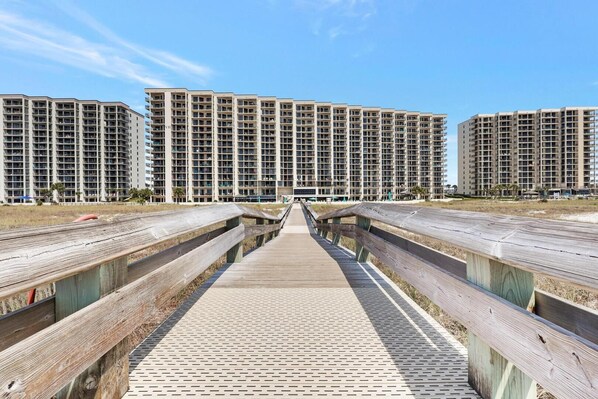 A boardwalk leading to high-rise buildings with multiple balconies.