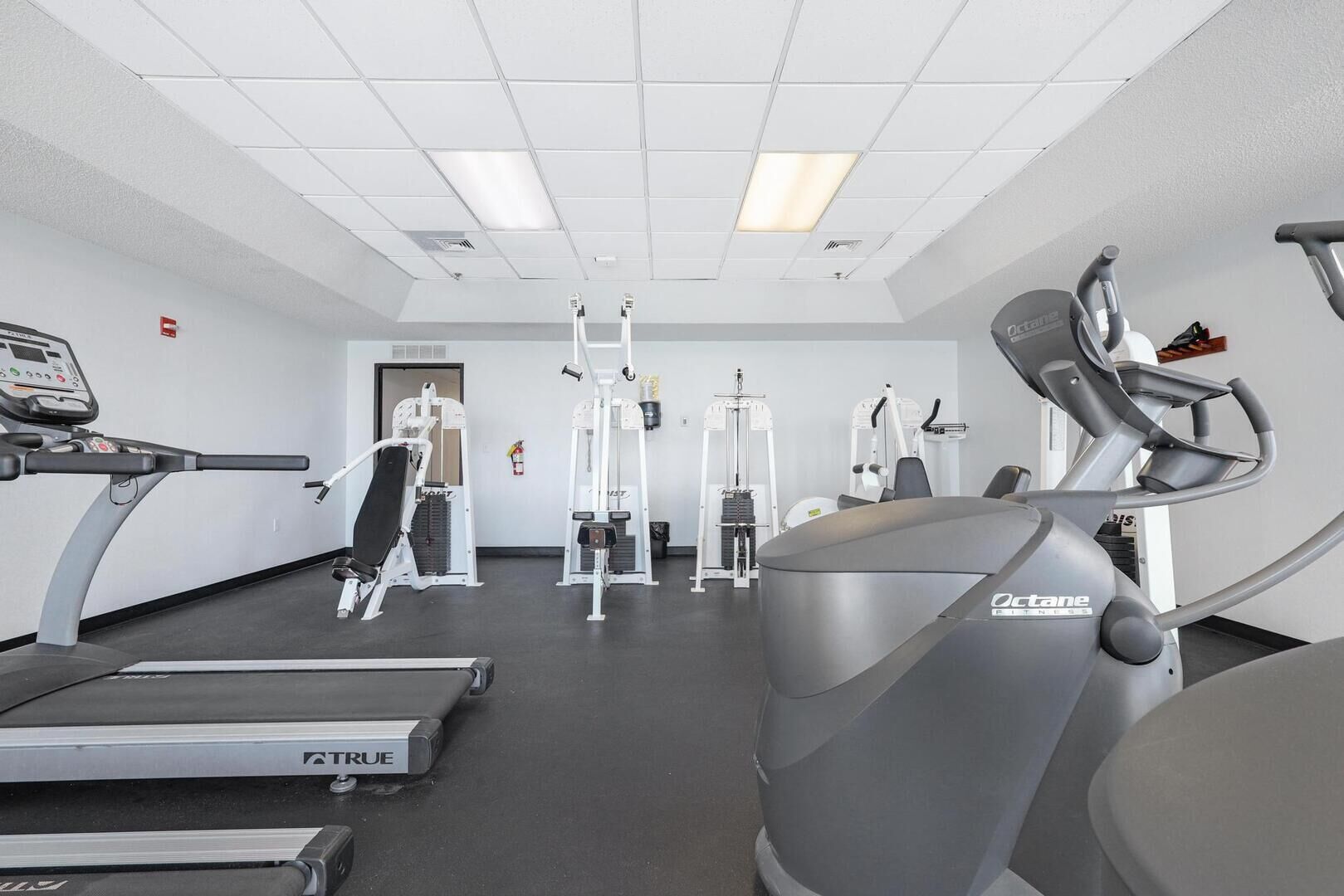 Une salle de sport équipée de tapis de course, de vélos elliptiques et d’appareils de musculation.