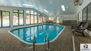 An indoor swimming pool with clear glass walls, a lifeguard chair, and a sign indicating no diving.
