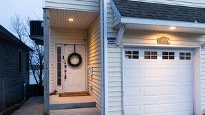 A residential garage with a white door and a garage number sign.
