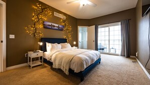 A bedroom with a bed, nightstand, wall art, and a ceiling fan.