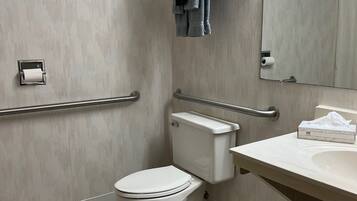 Een moderne badkamer met toilet, handgrepen, een wastafel en een handdoekrek.