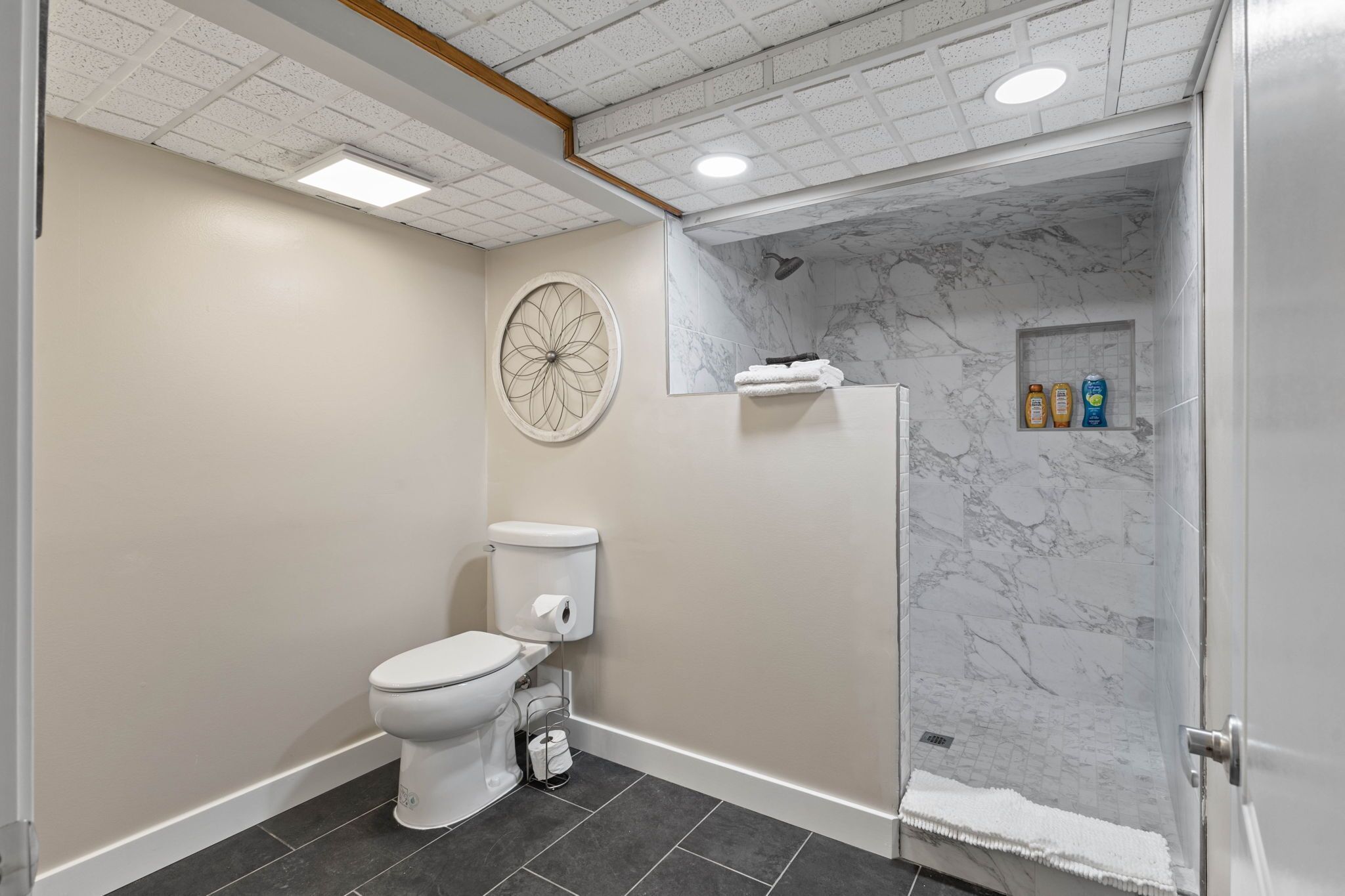 Un baño moderno con inodoro, ducha con paredes de mármol y barra para toallas.