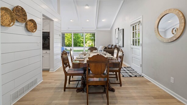 Un coin repas avec une table en bois dressée pour six personnes, entourée de chaises.