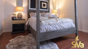 A four-poster bed with a wooden frame, two bedside tables with lamps, and a fluffy rug on the floor. - Diamond In The Rough (Oakland)