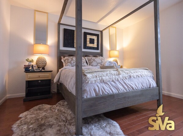 A four-poster bed with a wooden frame, two bedside tables with lamps, and a fluffy rug on the floor.