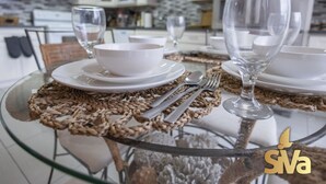A modern kitchen with white cabinets, a glass dining table with woven placemats, and a stainless steel refrigerator. - Diamond In The Rough (Oakland)