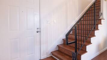 A staircase with wooden steps and black railings, leading to a door.