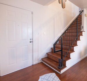A staircase with wooden steps and black railings, leading to a door. - Diamond In The Rough (Oakland)