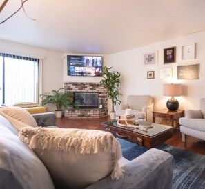 A living room with a fireplace, a television, and a comfortable seating area. - Diamond In The Rough (Oakland)