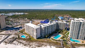 A high-rise hotel with multiple balconies, a swimming pool, and a beach area. - Beach View 3br/2ba W/pools Sleeps 8 (Orange Beach)