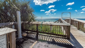 A wooden boardwalk leading to a beach with palm trees and a clear blue sky. - Beach View 3br/2ba W/pools Sleeps 8 (Orange Beach)