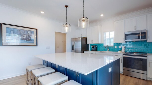 A modern kitchen with a large island, stainless steel appliances, and a teal backsplash. - Stunning 3br/2.5ba, Pet Friendly, Sleeps 12 (Orange Beach)