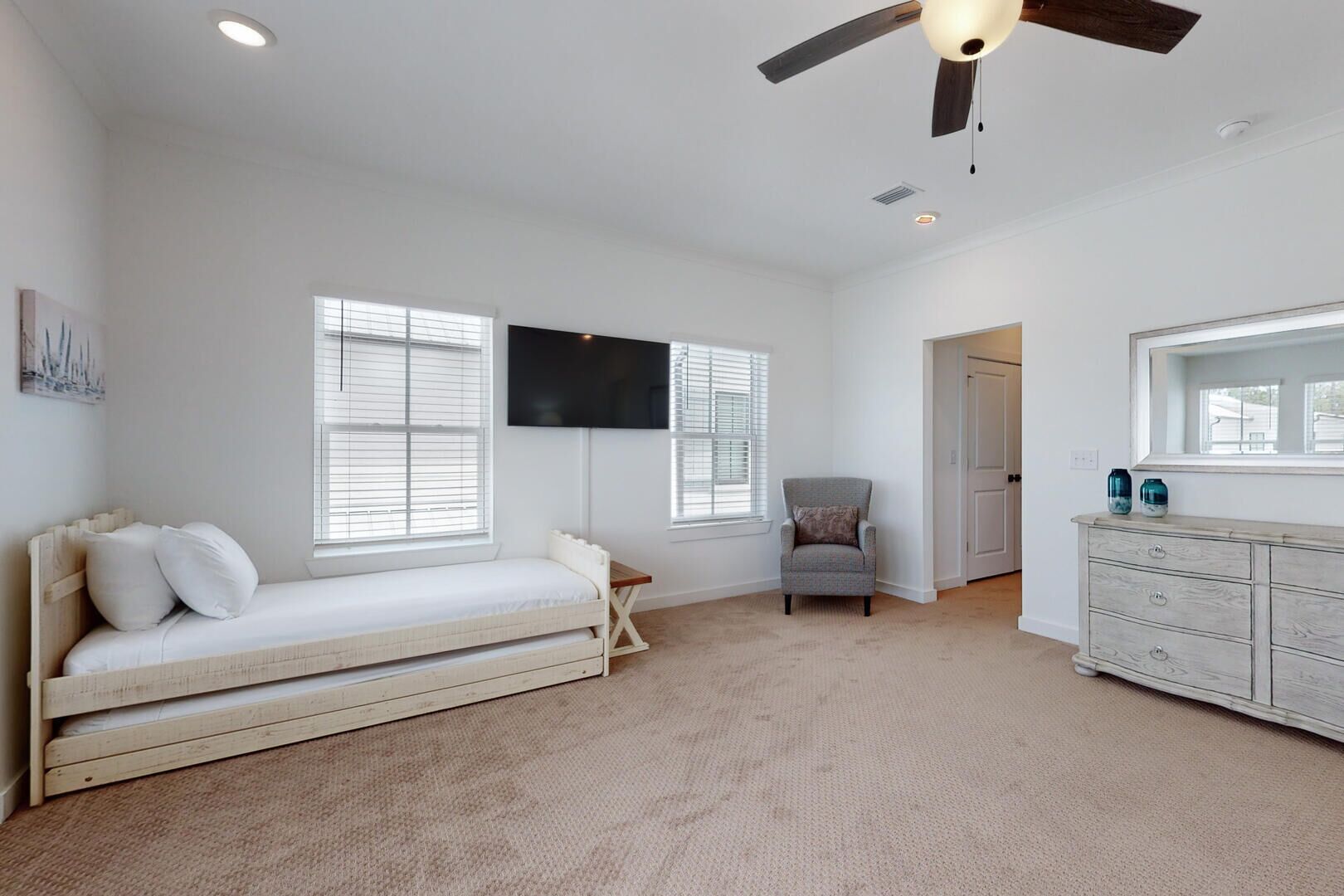A bedroom with a bed, a chair, a dresser, and a ceiling fan.