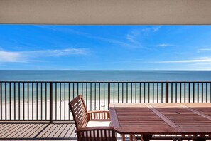 A wooden deck with a table and chairs overlooking a beach. - Beachfront Condo w/ View & Pool, Sleeps 8 (Orange Beach)
