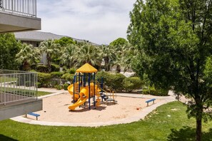 Ein Spielplatz mit einer gelben Rutsche und einer blauen Bank.
