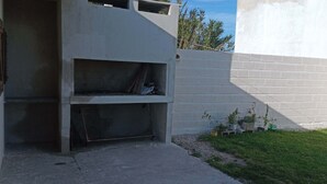 A concrete building with a small outdoor area, a metal mesh entrance, and a brick wall. - Casa Mis Suegros (Mar del Plata)