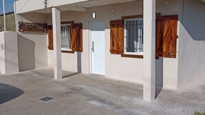 A building with a white exterior, a door, and windows with wooden shutters. - Casa Mis Suegros (Mar del Plata)