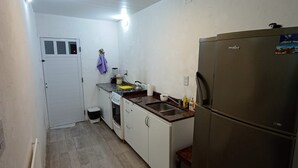 A compact kitchen with a refrigerator, stove, sink, and a small countertop. - Casa Mis Suegros (Mar del Plata)