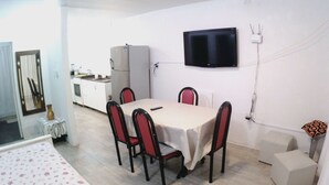 A compact room with a dining table, chairs, a flat-screen TV, a refrigerator, and a small kitchenette. - Casa Mis Suegros (Mar del Plata)