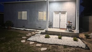 A modern two-story house with a covered porch, a double door, and a small patio area with a table and chairs. - 2-bedroom vacation home just 6 minutes from SoFi Stadium (Los Angeles)