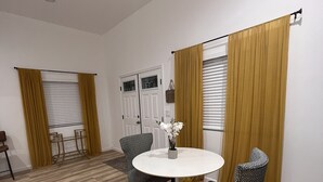 A dining area with a round table, two patterned chairs, a small side table, and a vase with flowers. - 2-bedroom vacation home just 6 minutes from SoFi Stadium (Los Angeles)