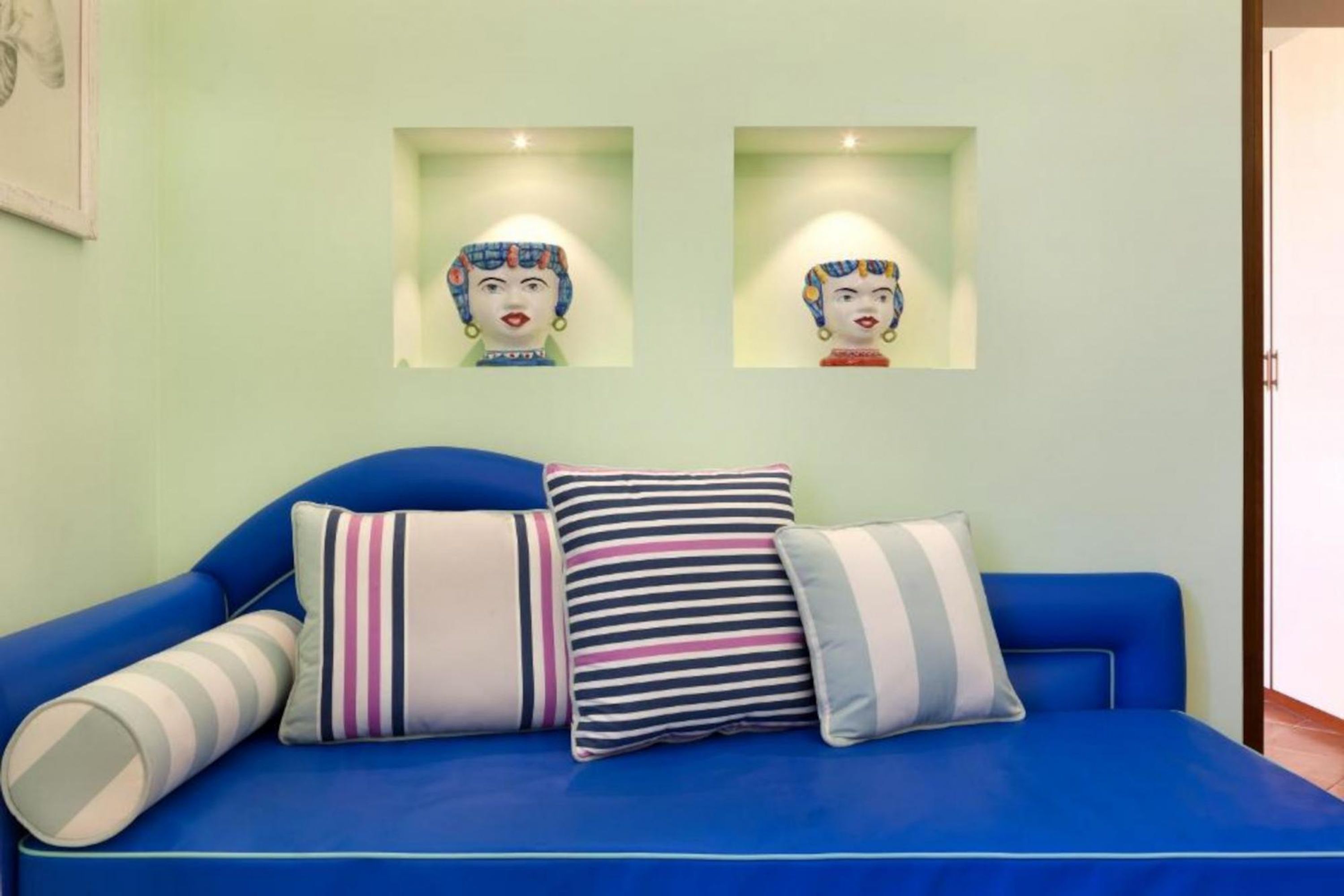 A blue sofa with striped pillows and two wall-mounted artworks.