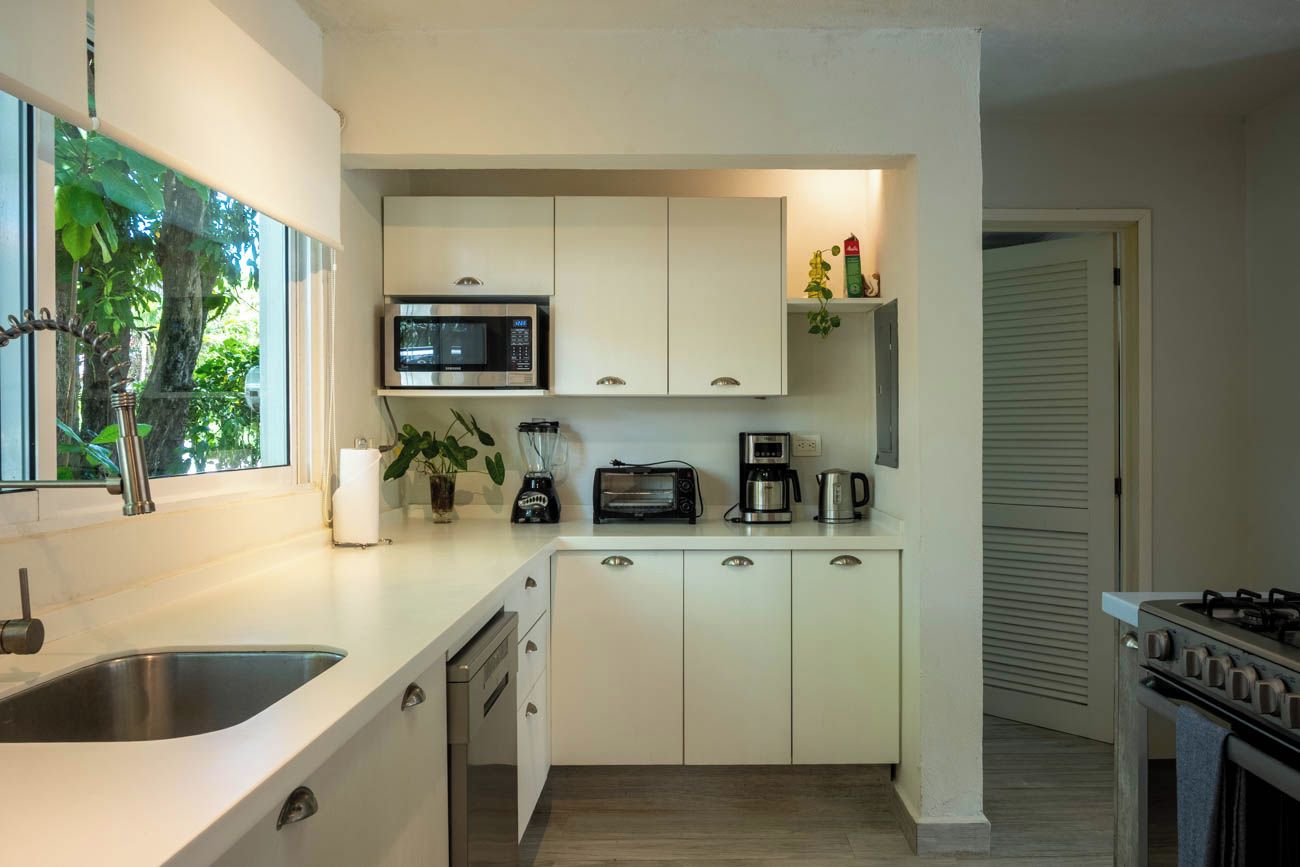 A compact kitchen with a microwave, toaster, coffee maker, and a sink.
