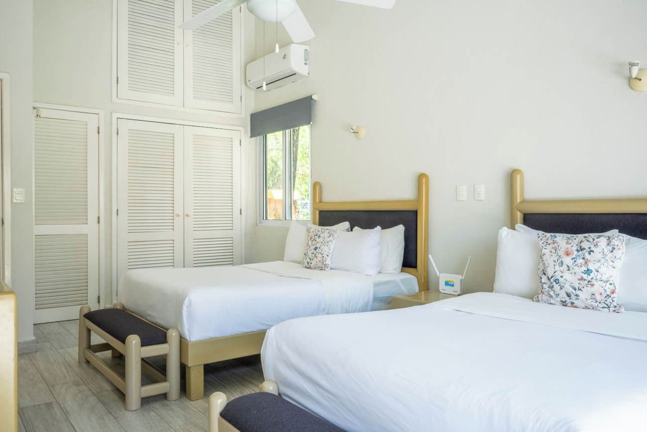 A hotel room with two beds, a window, and a ceiling fan.
