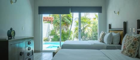 A bedroom with two beds, a ceiling fan, a view of a swimming pool, and a sliding glass door.