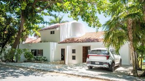 A white building with a tiled roof, a parked car, and surrounding greenery. - Matuk 3 (Playa del Carmen)