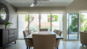 A dining area with a table and chairs, a ceiling fan, and large sliding glass doors leading to a patio. - Matuk 3 (Playa del Carmen)
