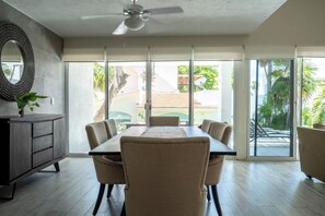 A dining area with a table and chairs, a ceiling fan, and large sliding glass doors leading to a patio. - Matuk 3 (Playa del Carmen)